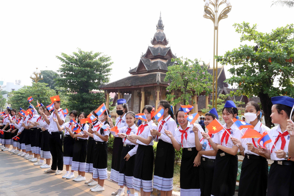 Các cháu thiếu nhi thủ đô Vientiane vẫy cờ hoa đón Chủ tịch nước Võ Văn Thưởng sang thăm chính thức Lào. (Ảnh: Thống Nhất/TTXVN)