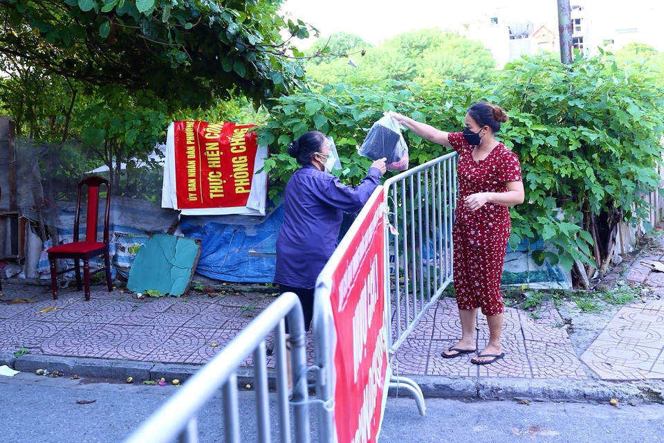 Người dân khu vực phong tỏa phường Việt Hưng nhận đồ tiếp tế từ bên ngoài chiều 18/9. (Ảnh: Hoàng Hiếu/TTXVN)