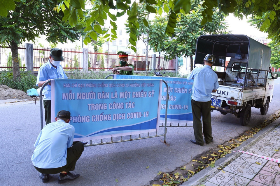 Lực lượng chức năng phường Việt Hưng (Long Biên) chuẩn bị rào chắn để phong tỏa khu vực. (Ảnh: Hoàng Hiếu/TTXVN)