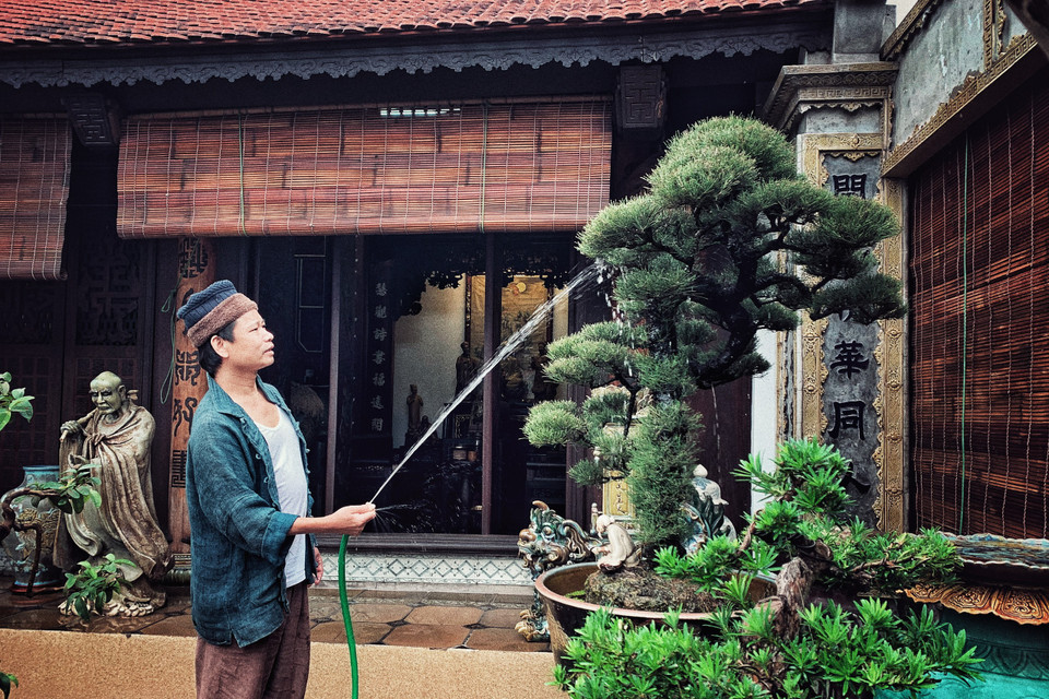 Một buổi sớm ngày cận Tết, vận chiếc quần đũi sắn ống thấp ống cao với đôi tông lào ngả màu, nghệ nhân ưu tú Trần Nam Tước say sưa tưới tắm cho vườn tiểu cảnh trên sân thượng. (Ảnh: Xuân Mai/Vietnam+)