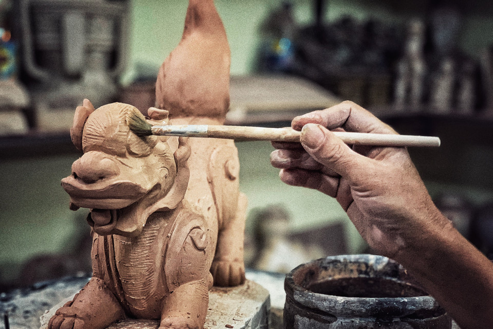 Để biến đất thành vàng, cùng một sản phẩm nhưng mỗi nghệ nhân có thể dùng các loại đất pha chế khác nhau, chất liệu màu khác nhau, thời gian nung qua lửa cũng như việc điều tiết nhiệt độ… khác nhau. (Ảnh: Xuân Mai/Vietnam+)