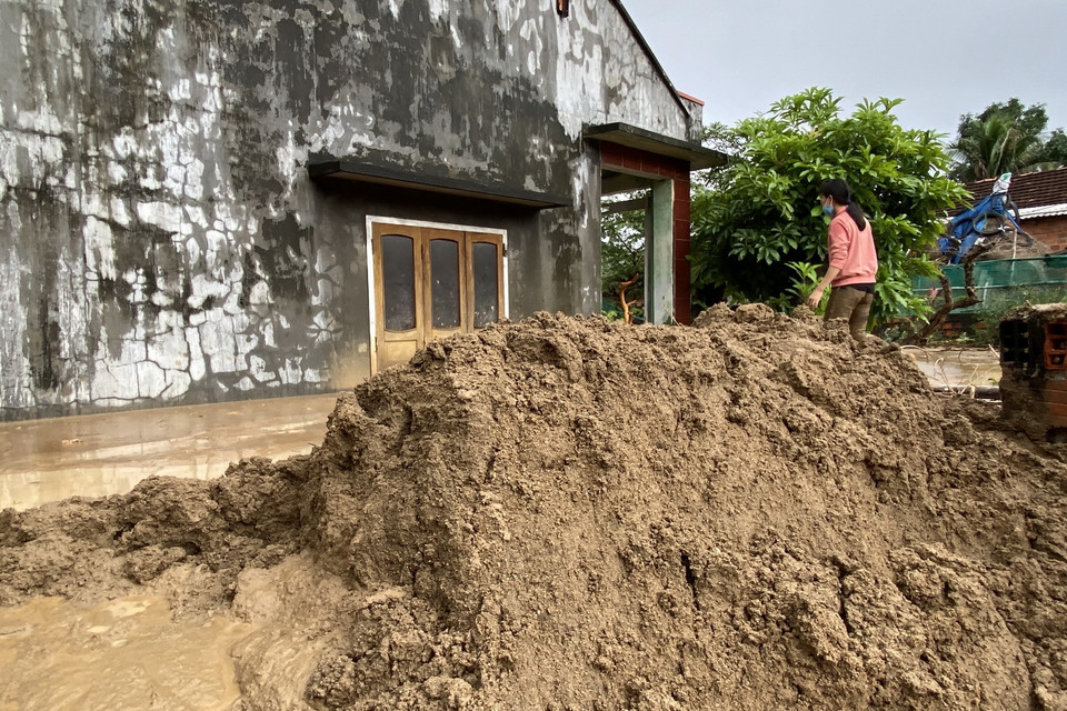  Chị Đặng Thị Hiền cố sức nạo vét bùn đất trôi vào nhà. (Ảnh: Tường Quân/TTXVN)