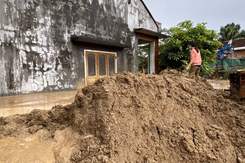  Chị Đặng Thị Hiền cố sức nạo vét bùn đất trôi vào nhà. (Ảnh: Tường Quân/TTXVN)