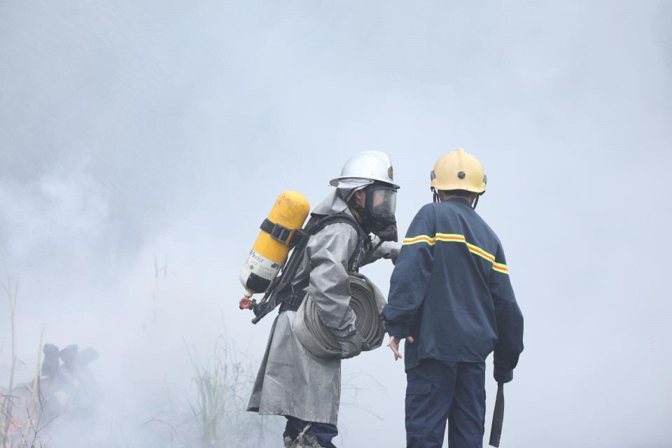 Các chiến sỹ phòng cháy chữa cháy tích cực khống chế ngọn lửa lây lan sang khu vực lân cận. (Ảnh: Thành Đạt/TTXVN)