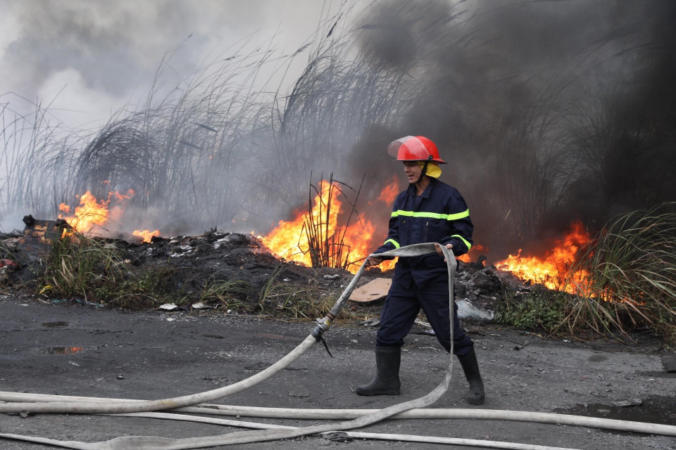Các chiến sỹ phòng cháy chữa cháy tích cực khống chế ngọn lửa lây lan sang khu vực lân cận. (Ảnh: Thành Đạt/TTXVN)