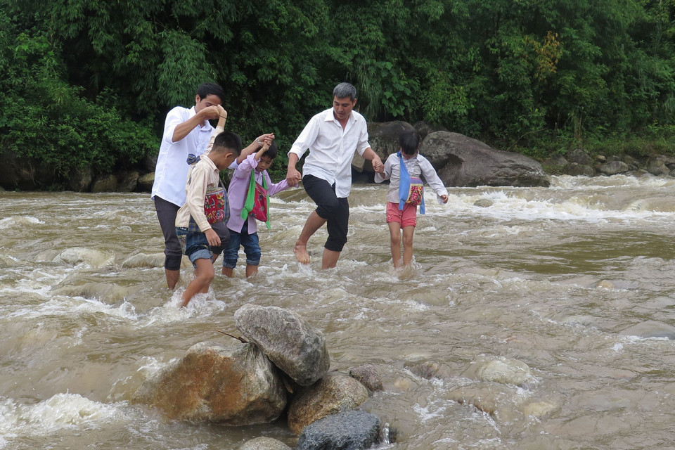 Giáo viên và học sinh trường Tiểu học số 2 xã Nậm Xe, huyện Phong Thổ, tỉnh Lai Châu băng qua suối để tới lớp học. (Ảnh: Việt Hoàng/TTXVN)