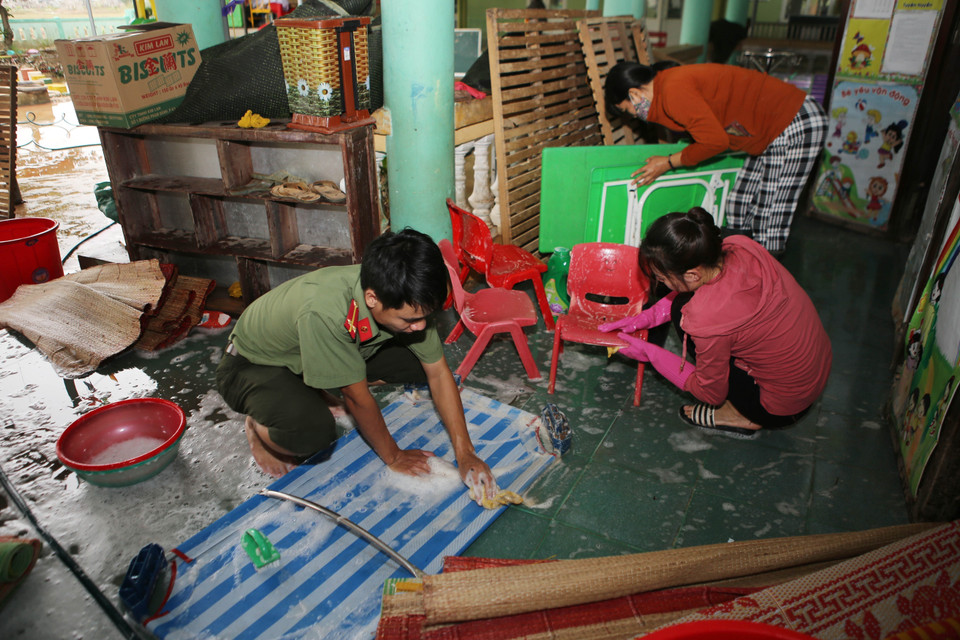 Chiến sỹ công an cùng thầy, cô giáo các trường học vùng thấp trũng ở huyện Triệu Phong (Quảng Trị) vệ sinh trường lớp, sẵn sàng đón học sinh đi học trở lạ sau khi nước lũ rút (15/10/2020). (Ảnh: Hồ Cầu/TTXVN)