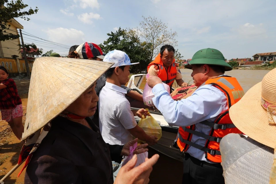 Bộ trưởng Bộ Kế hoạch Đầu tư Nguyễn Chí Dũng phát quà cứu trợ cho người dân tại huyện Lệ Thủy (Quảng Bình). (Ảnh: Thành Đạt/TTXVN)