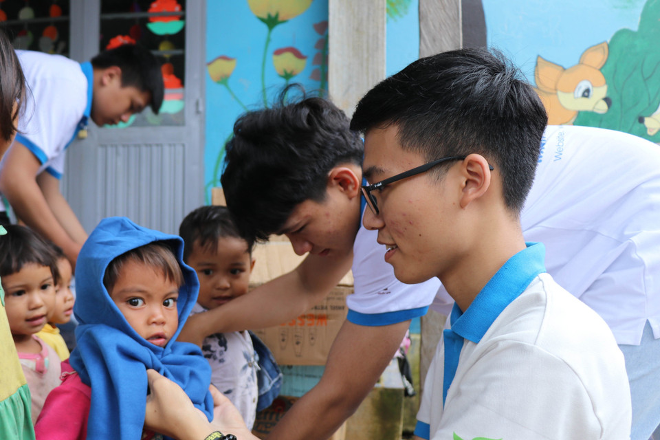  Các em học sinh nhóm thiện nguyện Fly to Sky mang áo ấm đến cho trẻ em làng Đê Kôn. (Ảnh: Hồng Điệp/TTXVN)