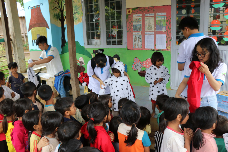 Các em học sinh nhóm thiện nguyện Fly to Sky mang áo ấm đến cho trẻ em làng Đê Kôn. (Ảnh: Hồng Điệp/TTXVN)