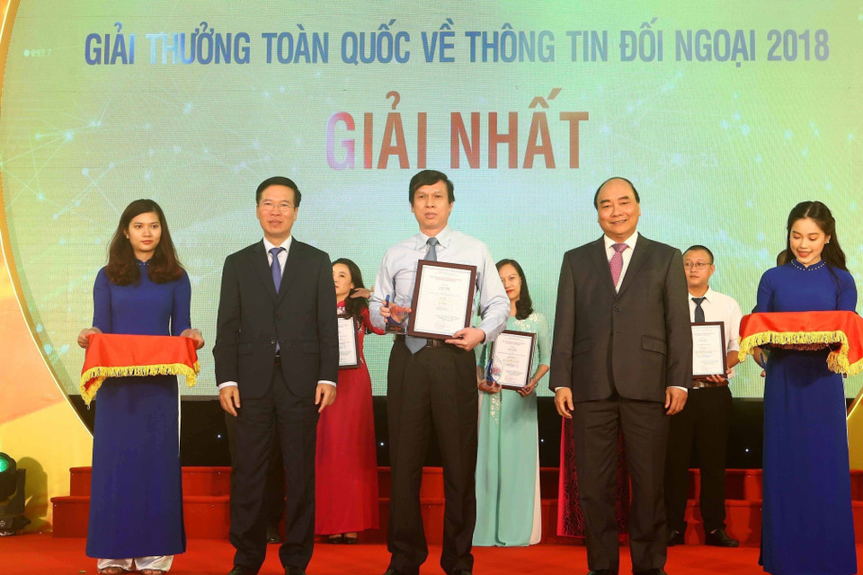 Thủ tướng Nguyễn Xuân Phúc và Trưởng ban Tuyên giáo Trung ương trao giải nhất Giải thưởng toàn quốc thông tin đối ngoại năm 2018 cho tác giả Lê Trí Dũng (TTXVN). (Ảnh: Doãn Tấn/TTXVN)