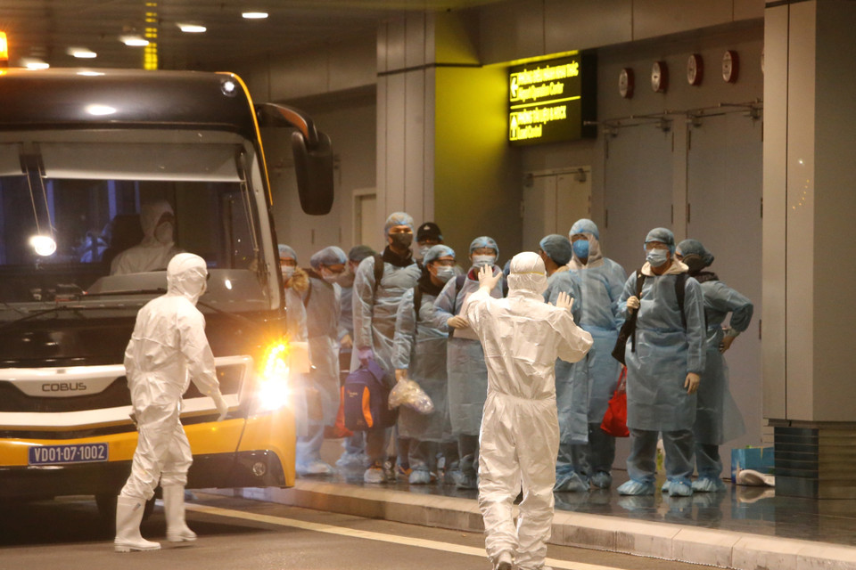 Lực lượng chức năng tại hiện trường hướng dẫn các công dân kiểm tra y tế và làm thủ tục nhập cảnh. (Ảnh: Dương Giang/TTXVN)