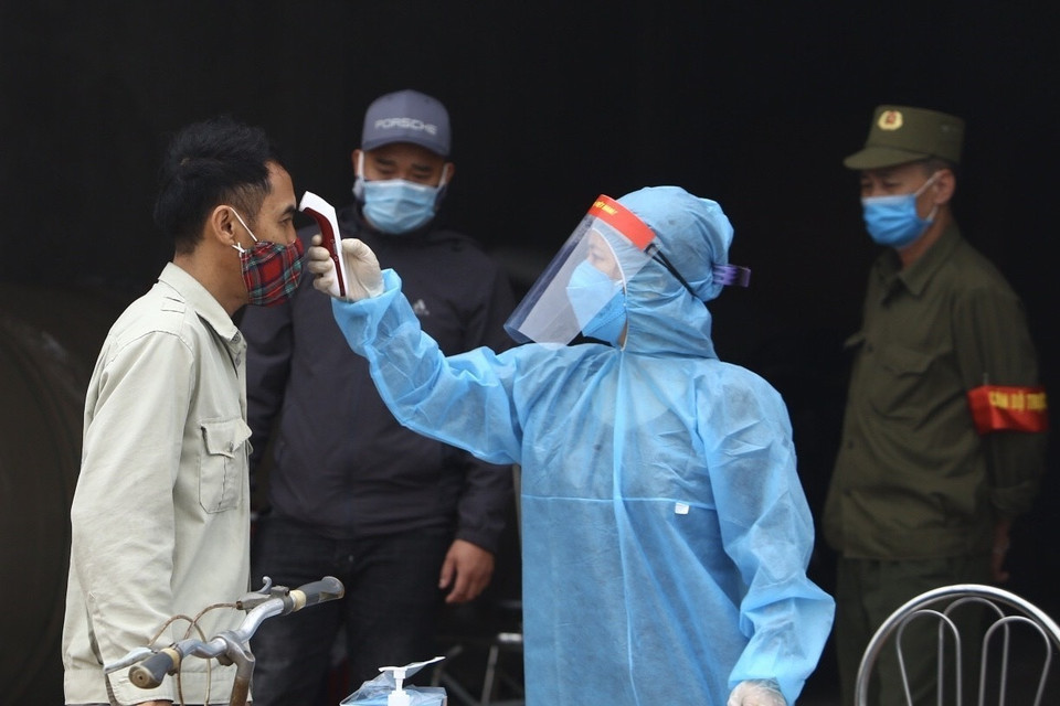  Nhân viên y tế kiểm tra thân nhiệt của người dân thôn Đông Cứu. (Ảnh: Minh Quyết/ TTXVN)