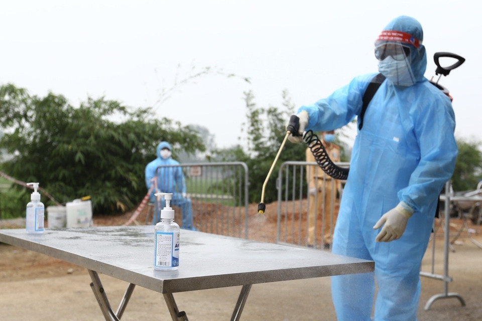 Phun khử khuẩn bàn để thực phẩm, hàng hóa trước khi chuyển vào thôn Đông Cứu. (Ảnh: Minh Quyết/ TTXVN)