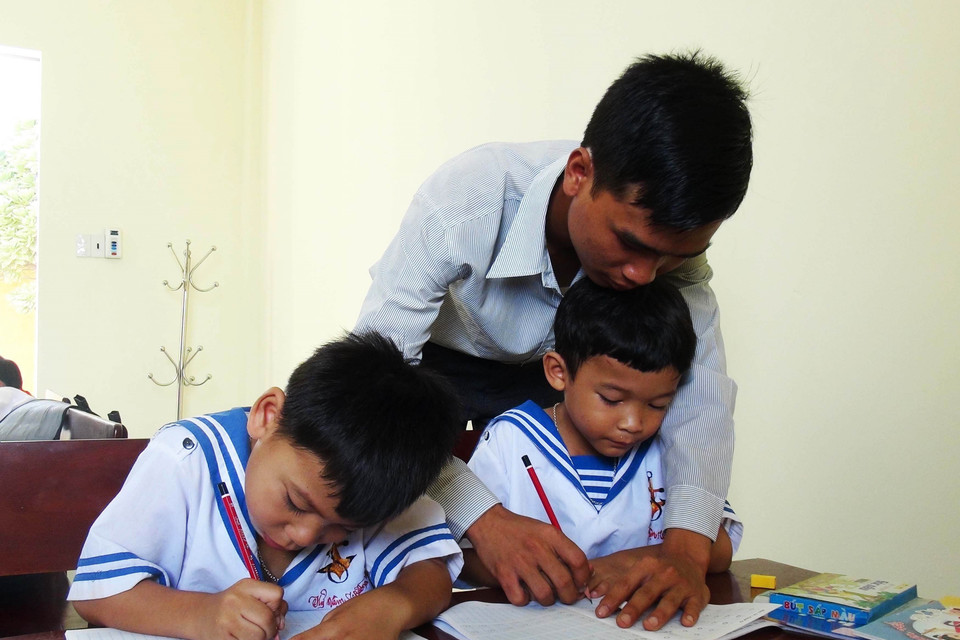 Thầy giáo Nguyễn Ngọc Hạ dạy viết chữ cho học sinh là con cán bộ, chiến sĩ, nhân dân trên xã đảo Sinh Tồn. (Ảnh: Nguyên Lý/TTXVN)