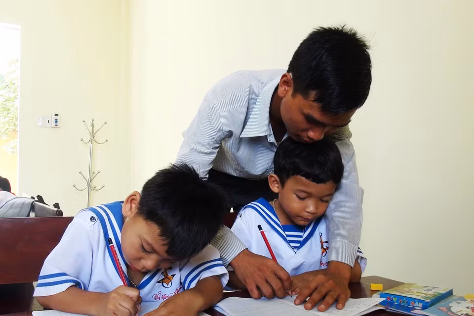 Thầy giáo Nguyễn Ngọc Hạ dạy viết chữ cho học sinh là con cán bộ, chiến sĩ, nhân dân trên xã đảo Sinh Tồn. (Ảnh: Nguyên Lý/TTXVN)