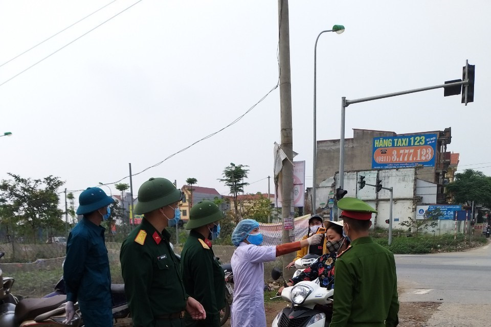 Kiểm soát thân nhiệt người dân tại chốt chặn ra vào thôn Hạ Lôi. (Ảnh: Nguyễn Cúc/TTXVN)