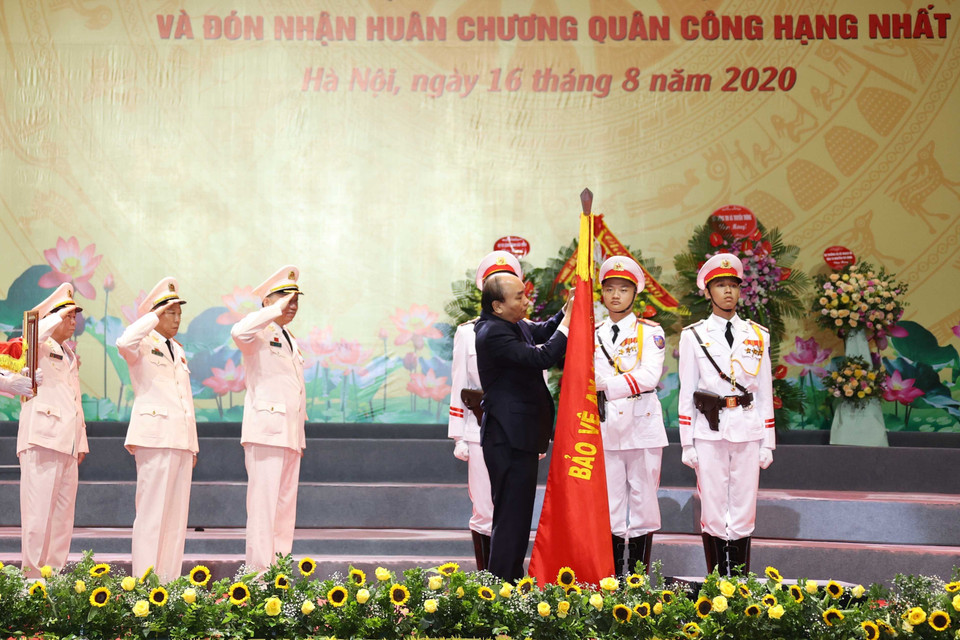 Thủ tướng Nguyễn Xuân Phúc gắn Huân chương Quân công hạng Nhất trên cờ truyền thống của lực lượng Công an nhân dân. (Ảnh: Thống Nhất/TTXVN)