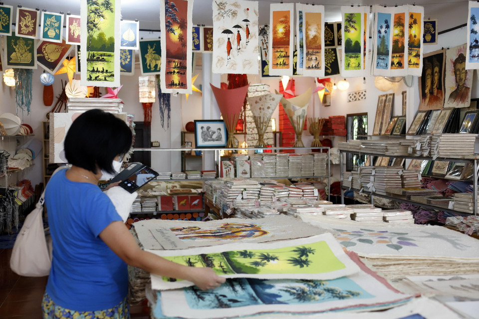 Du khách nước ngoài rất thích thú với các sản phẩm làm từ giấy Saa. (Ảnh: Phạm Kiên/TTXVN)