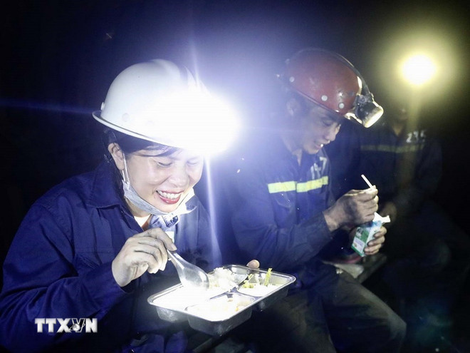 Phóng viên Thảo Nguyên của TTXVN và bữa cơm trưa muộn cùng thợ mỏ dưới hầm lò. (Ảnh: TTXVN) ttxvn-phong-vien-4.jpg