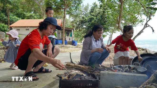 Du khách thích thú khi được tự tay chế biến các món ăn hải sản do mình bắt được ở đảo Hải Tặc. (Ảnh: Văn Sĩ/TTXVN) ttxvn-dao-hai-tac-2.jpg