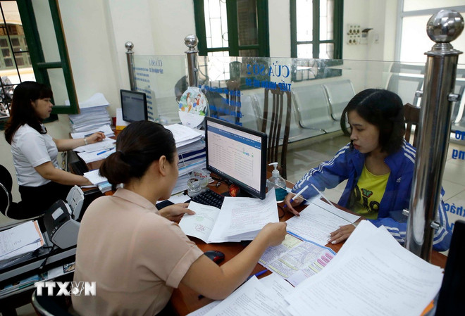 Personalul asigurărilor sociale din provincia Hung Yen îi îndrumă pe oameni prin procedurile de participare la asigurările sociale. (Foto: Pham Kien/VNA) ttxvn-bao-hiem-xa-hoi2.jpg