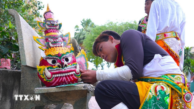 Em Binh Na Quinh, nghệ nhân trẻ Múa Chằn và Múa trống Chhay Dăm chuẩn bị mặt nạ chằng Krông Riêp cho tiết mục biểu diễn. (Ảnh: Minh Phú/TTXVN) ttxvn-mua-chan-4.jpg