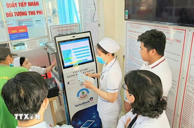 Staff of An Phu Medical Center, An Giang, guide people to register for medical examination and treatment using smart kiosks. (Photo: Cong Mao/VNA) ttxvn-chuyen-doi-so-chinh-quyen-2-cap-5.jpg