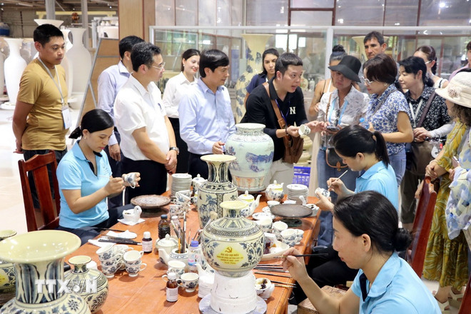 Các vị khách quốc tế thích thú tìm hiểu về quy trình sản xuất gốm Chu Đậu. (Ảnh: Mạnh Tú/TTXVN)