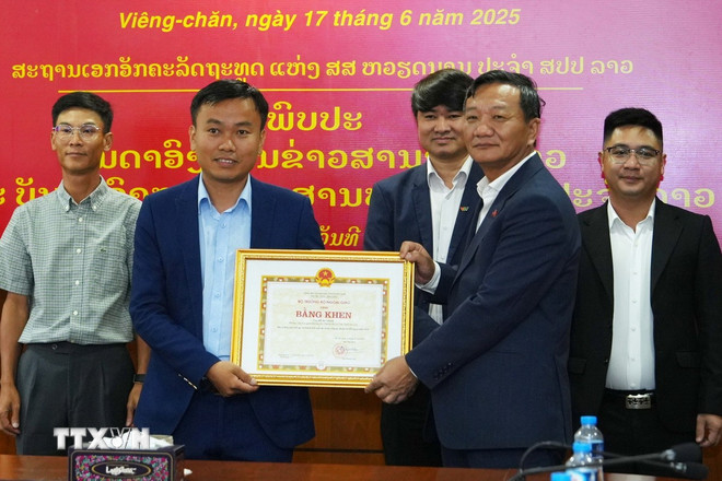 Đại sứ Việt Nam tại Lào Nguyễn Minh Tâm trao Bằng khen của Bộ trưởng Bộ Ngoại giao Việt Nam cho Phóng viên Cơ quan thường trú TTXVN tại Lào. (Ảnh: Xuân Tú/TTXVN) ttxvn-hop-tac-bao-chi-viet-nam-lao-2.jpg