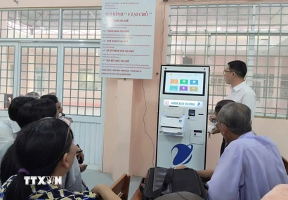 Cán bộ Trung tâm Phục vụ hành chính công xã Phú Lâm (tỉnh An Giang) hướng dẫn người dân các thao tác gửi, kiểm tra hồ sơ thủ tục hành chính bằng kiốt thông minh. (Ảnh: Công Mạo/TTXVN)