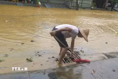 Người dân tổ 4 Duyên Hải, phường Lào Cai khơi thông cống rãnh thoát nước ngập úng. (Ảnh: Hương Thu/TTXVN)