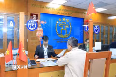 Cán bộ, công chức Trung tâm Phục vụ hành chính công thành phố Hà Nội-Chi nhánh số 3 hướng dẫn người dân hoàn thiện hồ sơ thủ tục hành chính. (Ảnh: TTXVN phát)