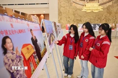 Các đại biểu xem trưng bày ảnh về thành tựu 75 năm quan hệ Việt-Trung. (Ảnh: Minh Đức/TTXVN)