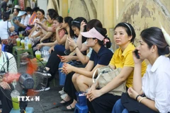 Bên ngoài điểm thi Trung học phổ thông Chu Văn An, nhiều phụ huynh ngồi đợi con. (Ảnh: Lê Đông/TTXVN)