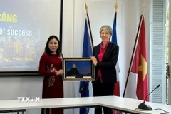 Bà Đinh Thị Lụa (trái) tặng quà cho bà Géraldine Lemblé - Phó Tổng giám đốc Liên đoàn Doanh nghiệp Pháp. (Ảnh: Đào Dũng/TTXVN)