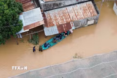 Người dân di chuyển bằng thuyền tại khu vực ngập nước tại xã Ninh Phước (Khánh Hòa). (Ảnh: Nguyễn Thành/TTXVN)