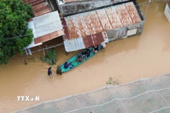 Người dân di chuyển bằng thuyền tại khu vực ngập nước tại xã Ninh Phước (Khánh Hòa). (Ảnh: Nguyễn Thành/TTXVN)