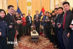 Cán bộ, nhân viên Đại sứ quán Việt Nam và Đại sứ quán Lào tại Pháp nâng cốc chúc mừng nhân kỷ niệm 50 năm Quốc khánh Lào (2/12/1975). (Ảnh: Hữu Chiến/TTXVN)