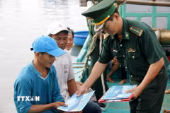 Cấp phát tài liệu chống khai thác IUU cho ngư dân. (Ảnh: Hồng Hiếu/TTXVN)