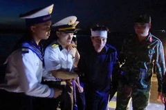 Các chiến sỹ đảo Trường Sa dìu bệnh nhân Tiêu Viết Bút đến Trung tâm y tế. (Ảnh: TTXVN phát)