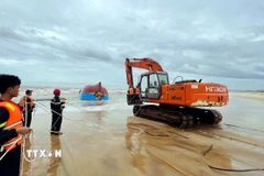 Lực lượng chức năng tỉnh Quảng Trị huy động lực lượng, phương tiện trục vớt tàu BV-92756-TS để tìm kiếm thuyền viên bên trong. (Ảnh: Nguyên Linh/TTXVN)