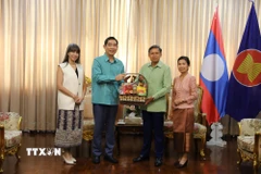 Đại sứ Phạm Việt Hùng (trái) và phu nhân trao lẵng quà tặng Đại sứ Lào Sisavath Inphachanh và phu nhân. (Ảnh: Đỗ Sinh/TTXVN)