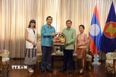 Đại sứ Phạm Việt Hùng (trái) và phu nhân trao lẵng quà tặng Đại sứ Lào Sisavath Inphachanh và phu nhân. (Ảnh: Đỗ Sinh/TTXVN)