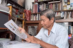 Ông Trần Hữu Huệ xem bì thư dán tem về Hoàng Sa được gửi từ nước ngoài, một hiện vật quý trong bộ sưu tập tem về chủ quyền biển, đảo Việt Nam. (Ảnh: Thanh Sang/TTXVN)