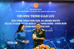 Trung tướng Phạm Tuân tặng chị Amanda Nguyễn cuốn sách kỷ niệm ghi dấu chuyến bay lịch sử của ông. (Ảnh: TTXVN phát)