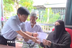 Ông Nguyễn Ngọc Huynh, Bí thư Đảng ủy, Chủ tịch Hội đồng Nhân dân xã Vĩnh Hậu (tỉnh An Giang), trao tiền hỗ trợ bước đầu cho các gia đình bị thiệt hại do hỏa hoạn tại ấp La Ma. (Ảnh: TTXVN phát)