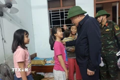 Phó Thủ tướng Thường trực Nguyễn Hòa Bình động viên các cháu học sinh được các lực lượng ứng cứu từ vùng ngập sâu. (Ảnh: Tuấn Anh/TTXVN)