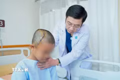 Tiến sỹ, bác sỹ Trương Thanh Tình, Trưởng Khoa Ngoại Thần kinh-Bệnh viện Đại học Y dược Thành phố Hồ Chí Minh thăm khám cho bệnh nhi sau phẫu thuật. (Ảnh: TTXVN phát)