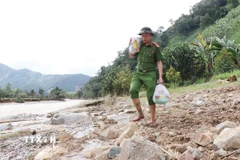 Lực lượng công an tiếp tế nhu yếu phẩm cứu trợ người dân vùng lũ xã Bác Ái Tây (Khánh Hòa). (Ảnh: Nguyễn Thành/TTXVN)